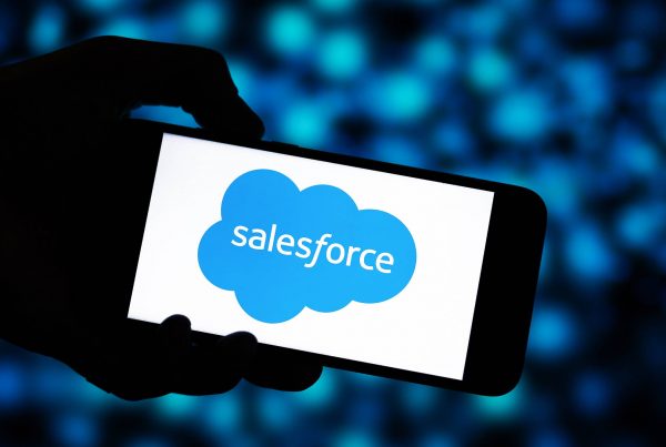 mobilke phone with salesforce logo on with lights blurred in background.